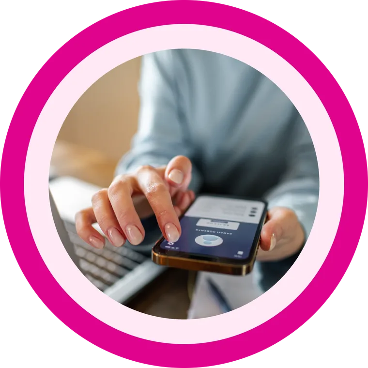 A business owner using the MobeX app on her phone beside her laptop