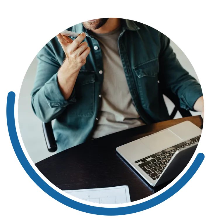 A business owner on a call at their desk, laptop open beside them